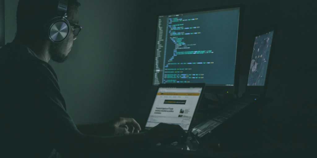 Man working on computers in the dark