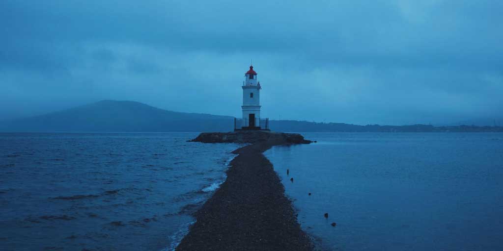 Lighthouse on a small island with thin strip of land connecting