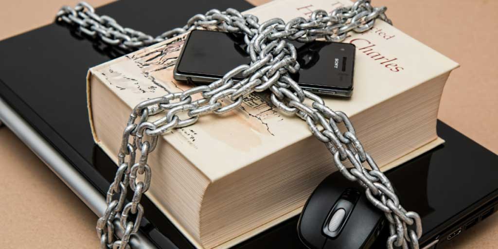 laptop, book and mobile phone chained together