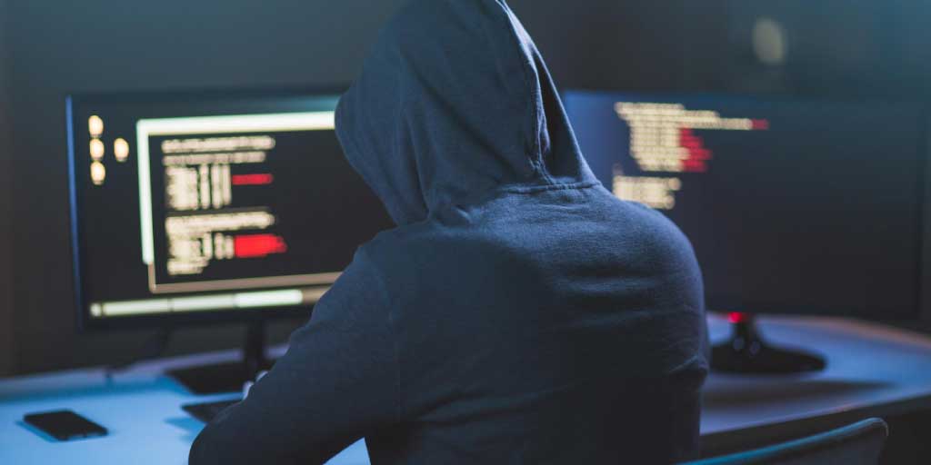 hacker in a hooded jacket on a computer