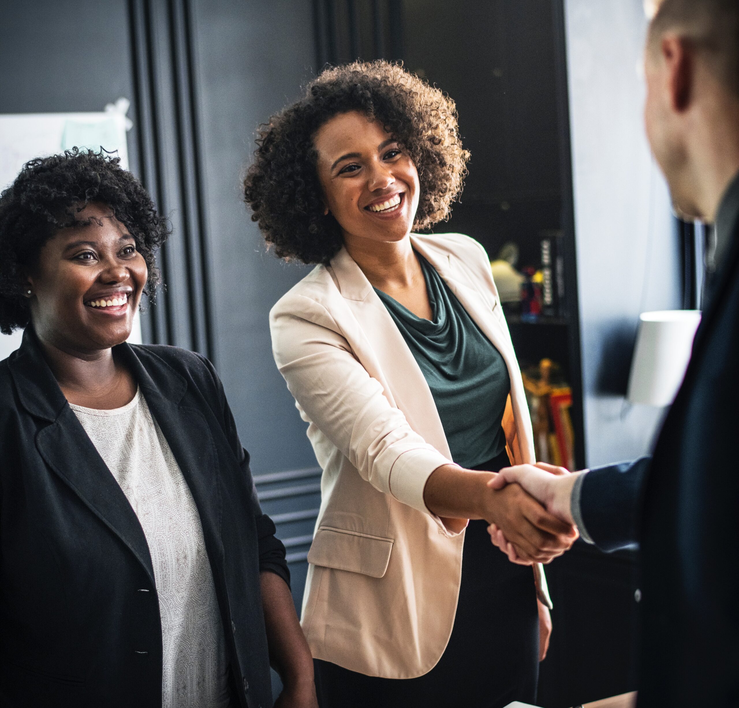 Business people shaking hands. Woman standing off to the side.