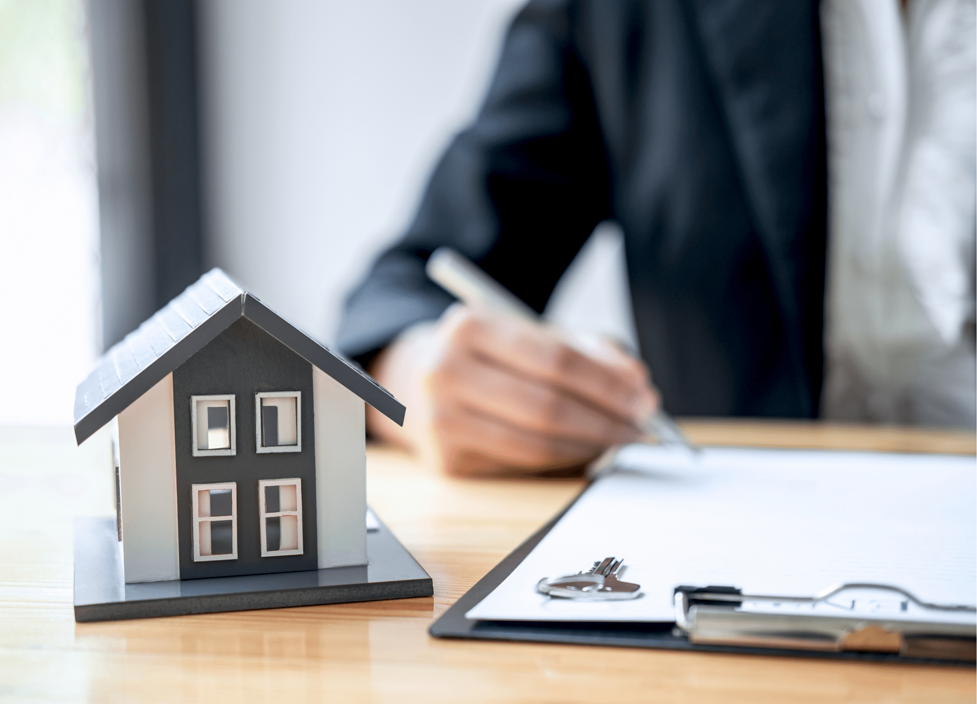 Mini house and person writing on clipboard