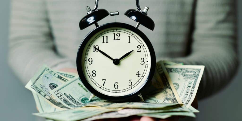 Person holding a round clock and money