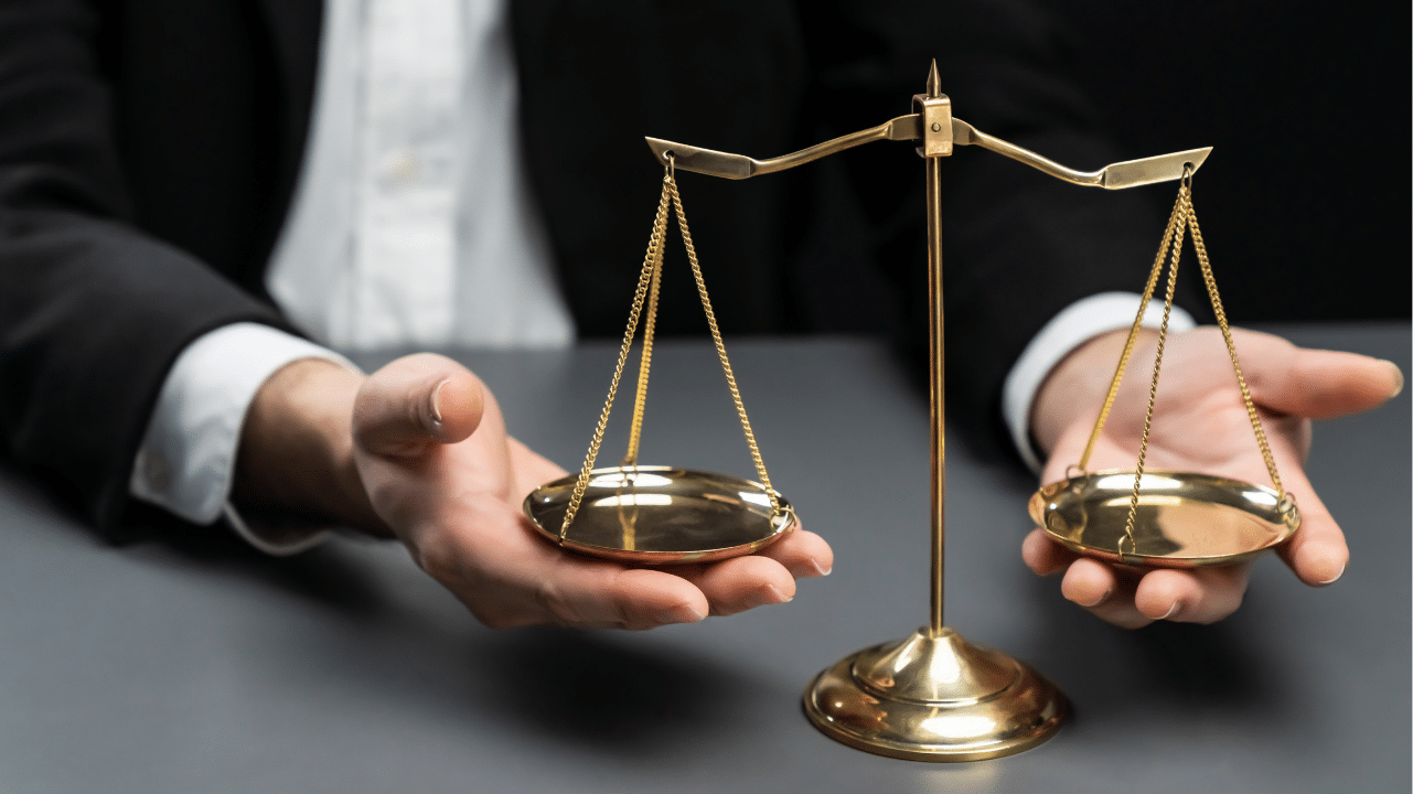 Lawyer in a black suit sits attentively at his office desk with a golden scale balance.